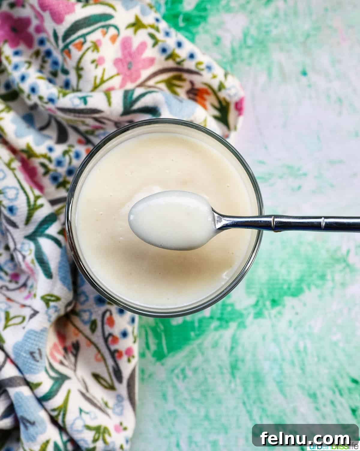 A spoonful of pudding held above a parfait bowl filled with homemade vanilla pudding.