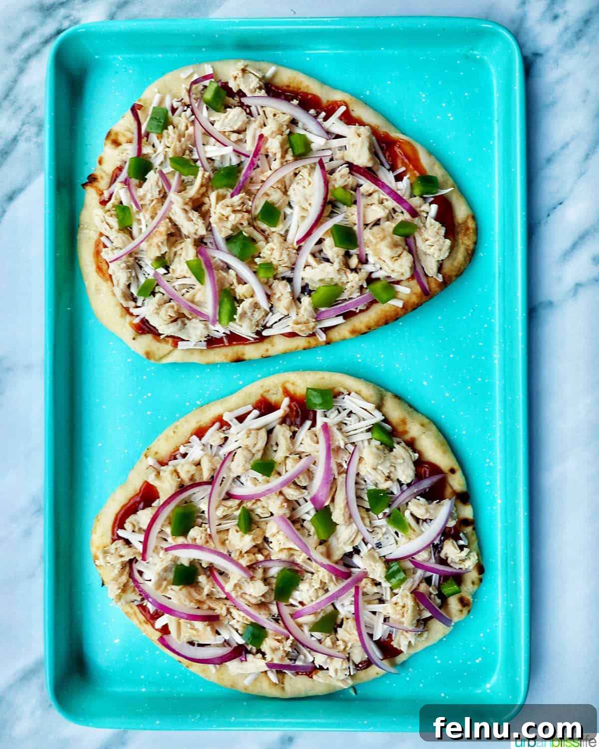 BBQ Chicken Flatbread Feast 13 Two BBQ chicken flatbread pizzas on a blue baking sheet, fresh out of the oven.
