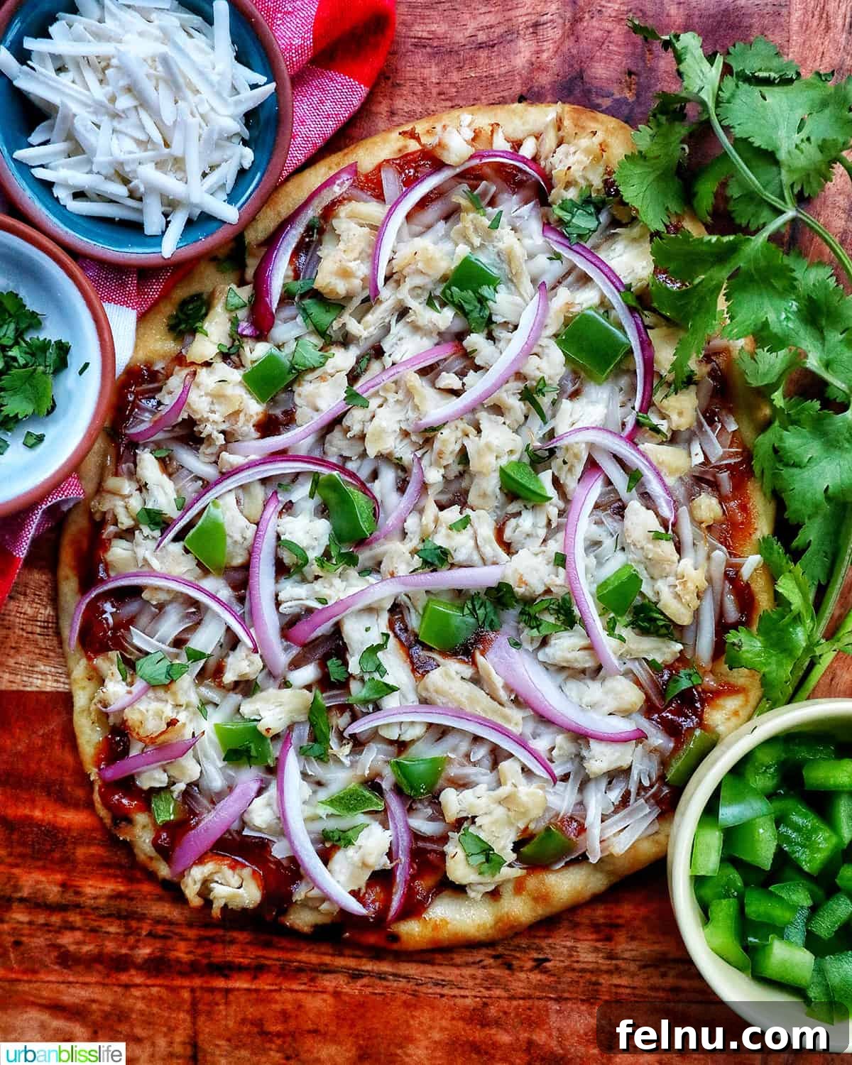 BBQ Chicken Flatbread Feast 3 Close-up of a BBQ chicken flatbread pizza with toppings like red onions, chicken, green peppers, and cilantro on a wooden board.