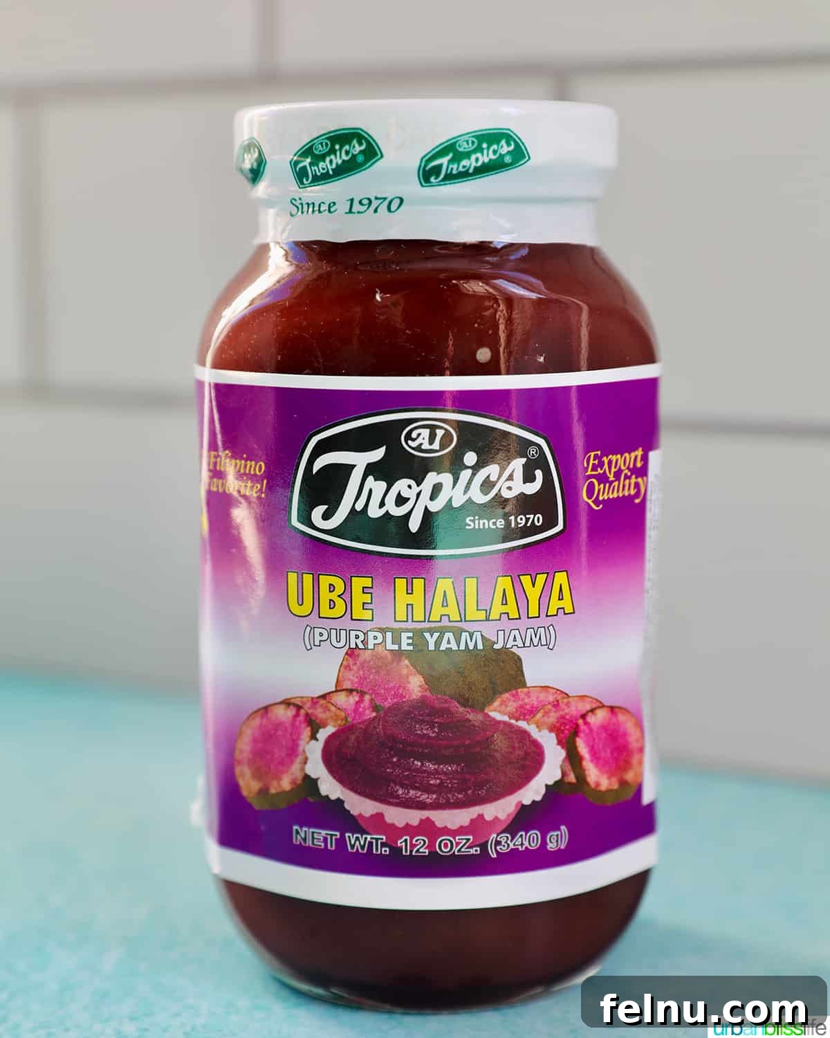 Over 30 Delectable Asian Dessert Ideas 6 A jar of homemade Ube Halaya (Ube Jam) sitting on a blue table with a white tile background.