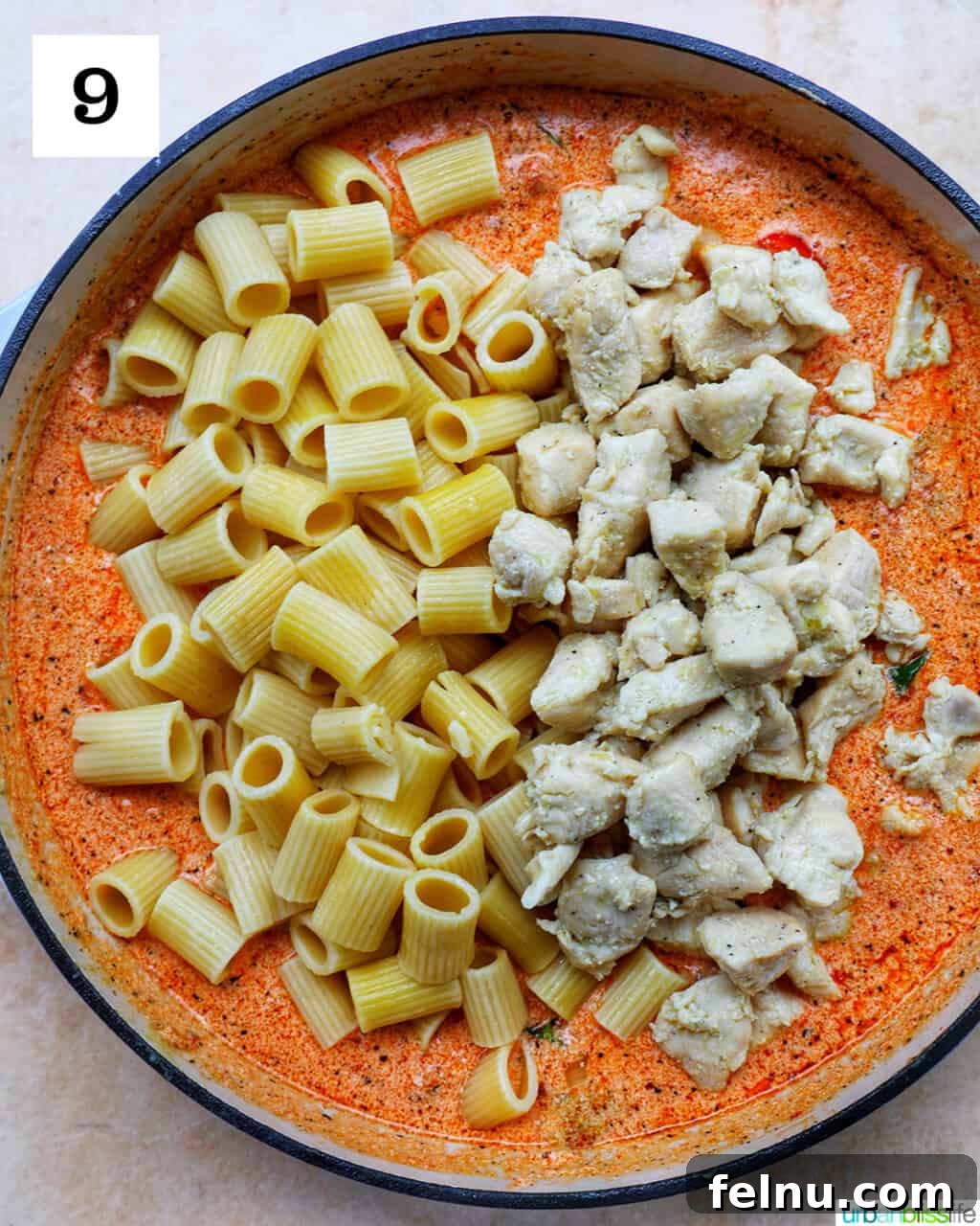Velvety Tuscan Chicken Pasta 15 Cooked rigatoni pasta and cubed chicken being added to the creamy sun-dried tomato sauce in a large skillet.