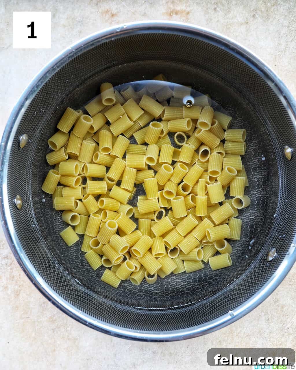 Velvety Tuscan Chicken Pasta 5 Rigatoni pasta boiling in a large pot of salted water on the stovetop.