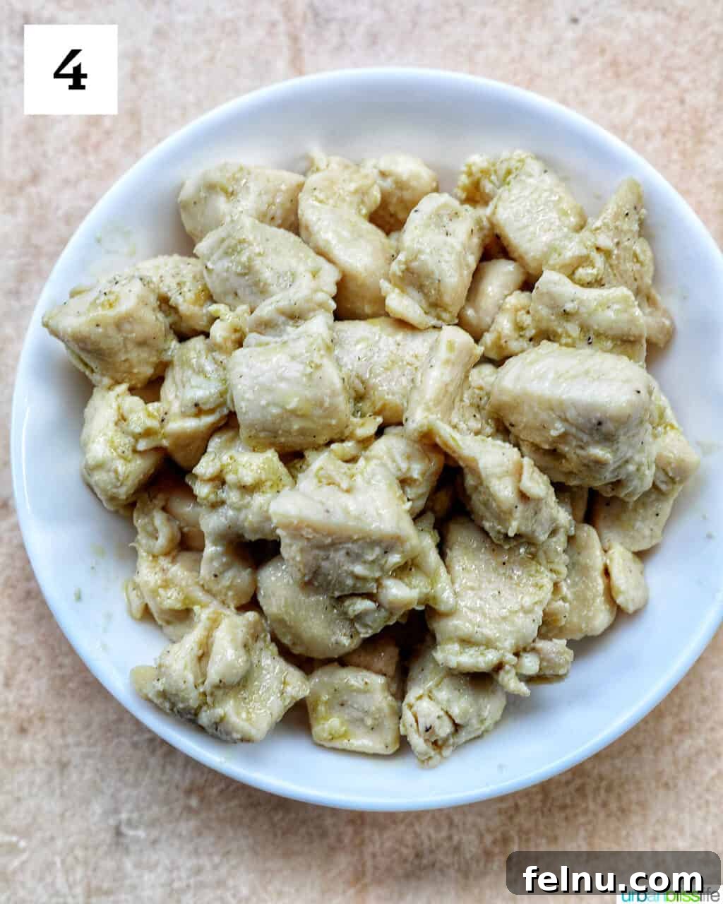 Velvety Tuscan Chicken Pasta 8 Cooked chicken cubes, golden brown, resting in a white bowl after being removed from the skillet.