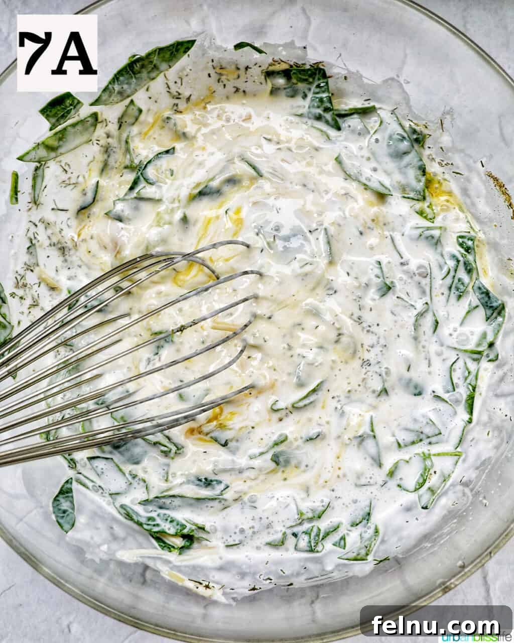 Smoked Salmon & Dill Quiche 13 A whisk actively blending eggs, heavy cream, and green herbs in a bowl, creating a smooth and creamy quiche filling.