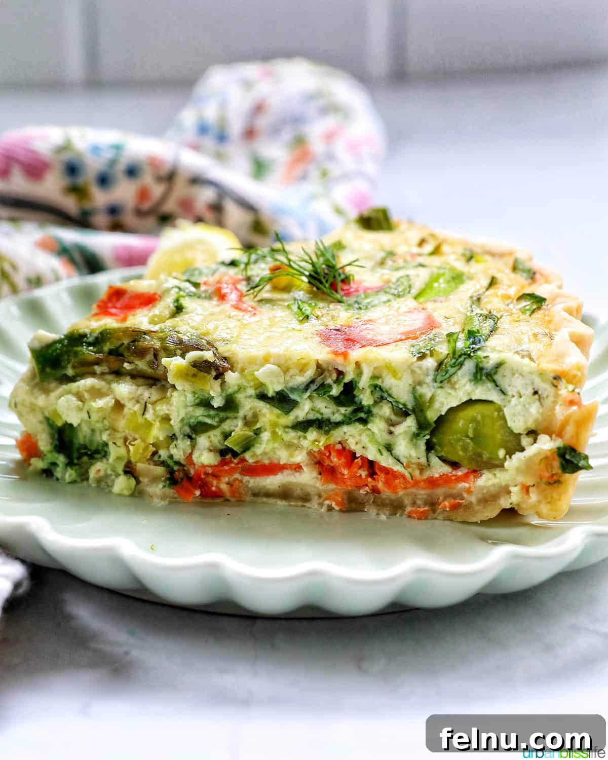 Smoked Salmon & Dill Quiche 20 A close-up side view of a slice of Salmon Quiche on a plate, revealing its beautifully layered interior with salmon, asparagus, and creamy egg.