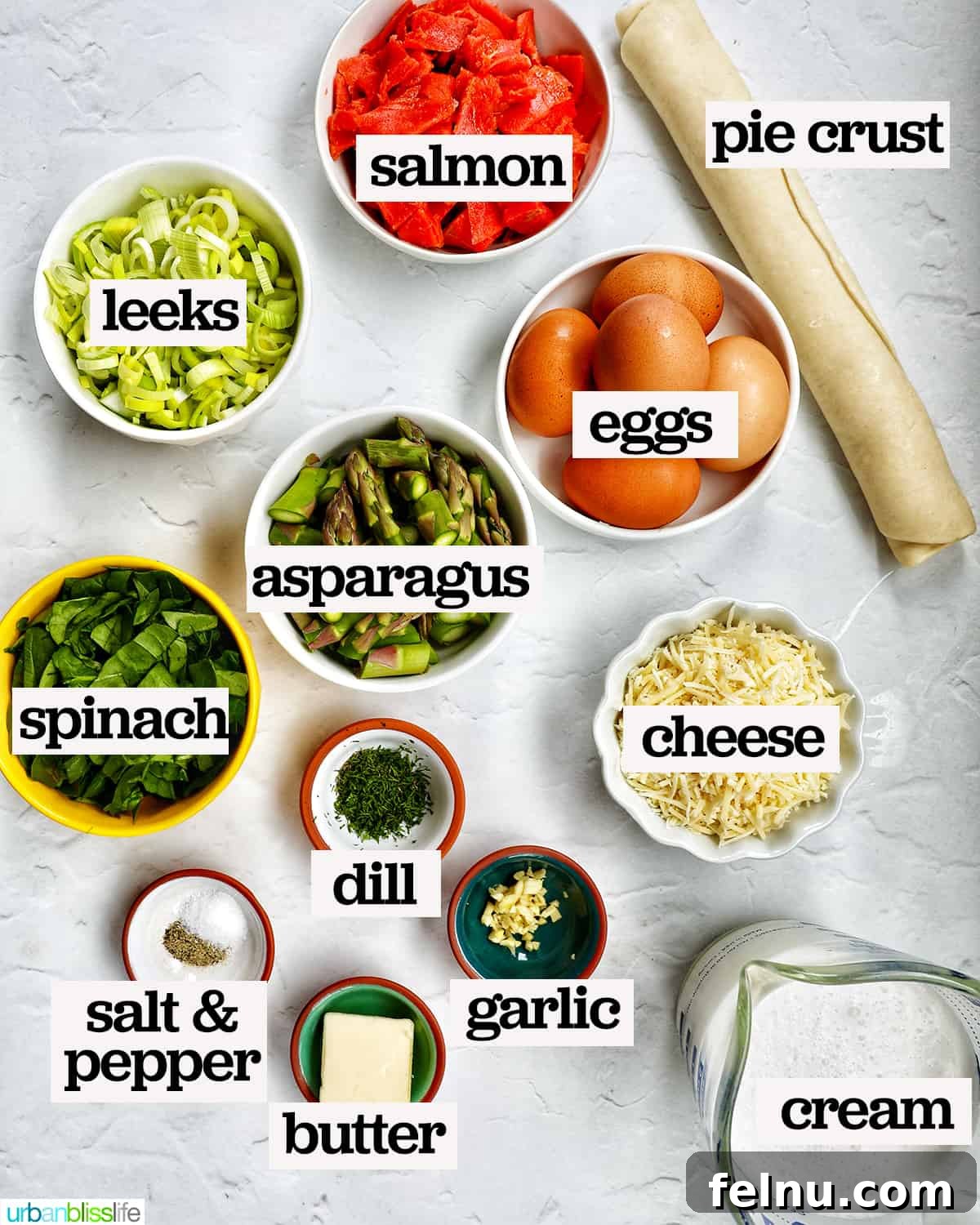 Smoked Salmon & Dill Quiche 5 Bowls of fresh ingredients neatly arranged for making a Salmon Quiche, including salmon, asparagus, leeks, eggs, and cheese.