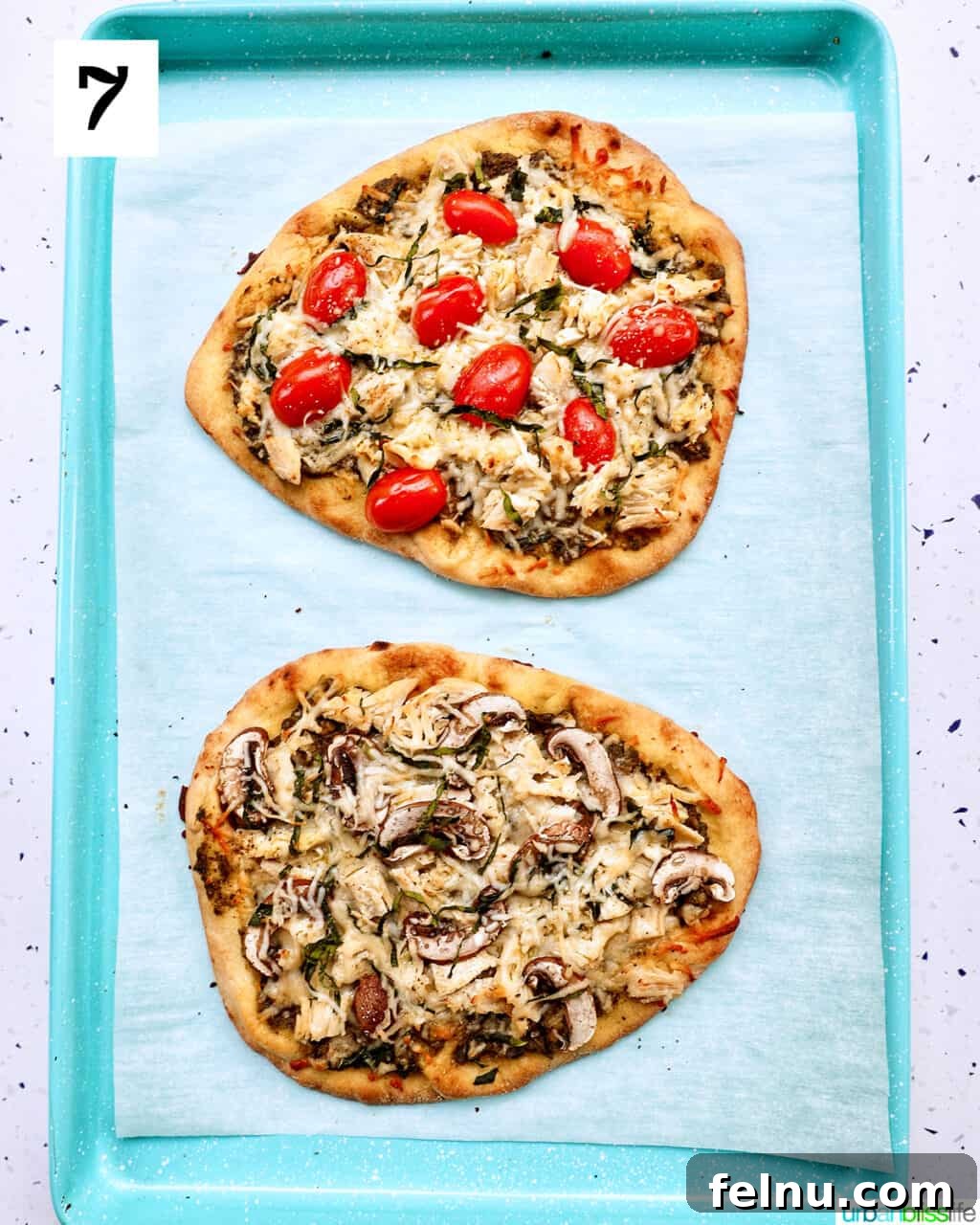 two freshly baked chicken pesto flatbreads, one with tomatoes and one with mushrooms, removed from the oven and perfectly golden.