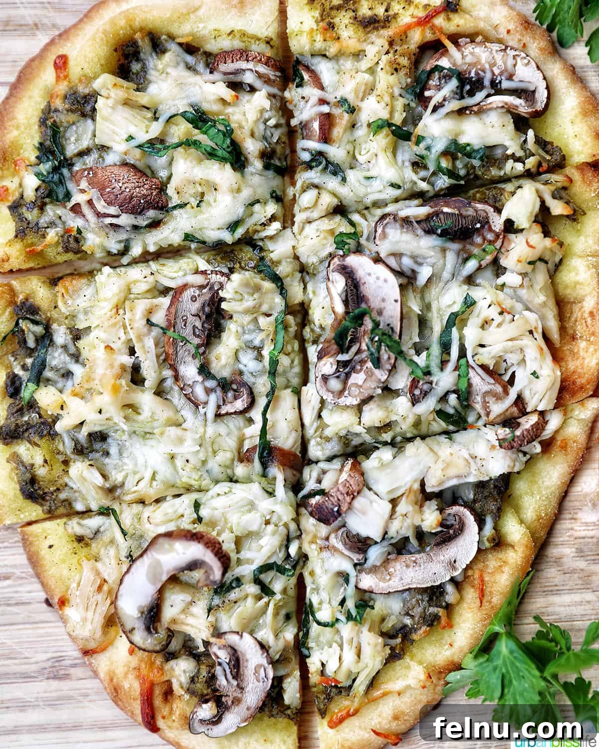 chicken pesto flatbread with mushrooms on a wooden board, sliced and ready to eat.