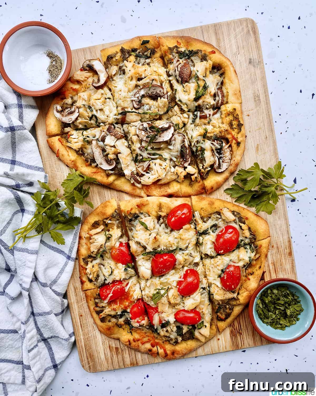 two chicken pesto flatbreads, one with tomatoes and one with mushrooms, freshly baked and ready to slice.