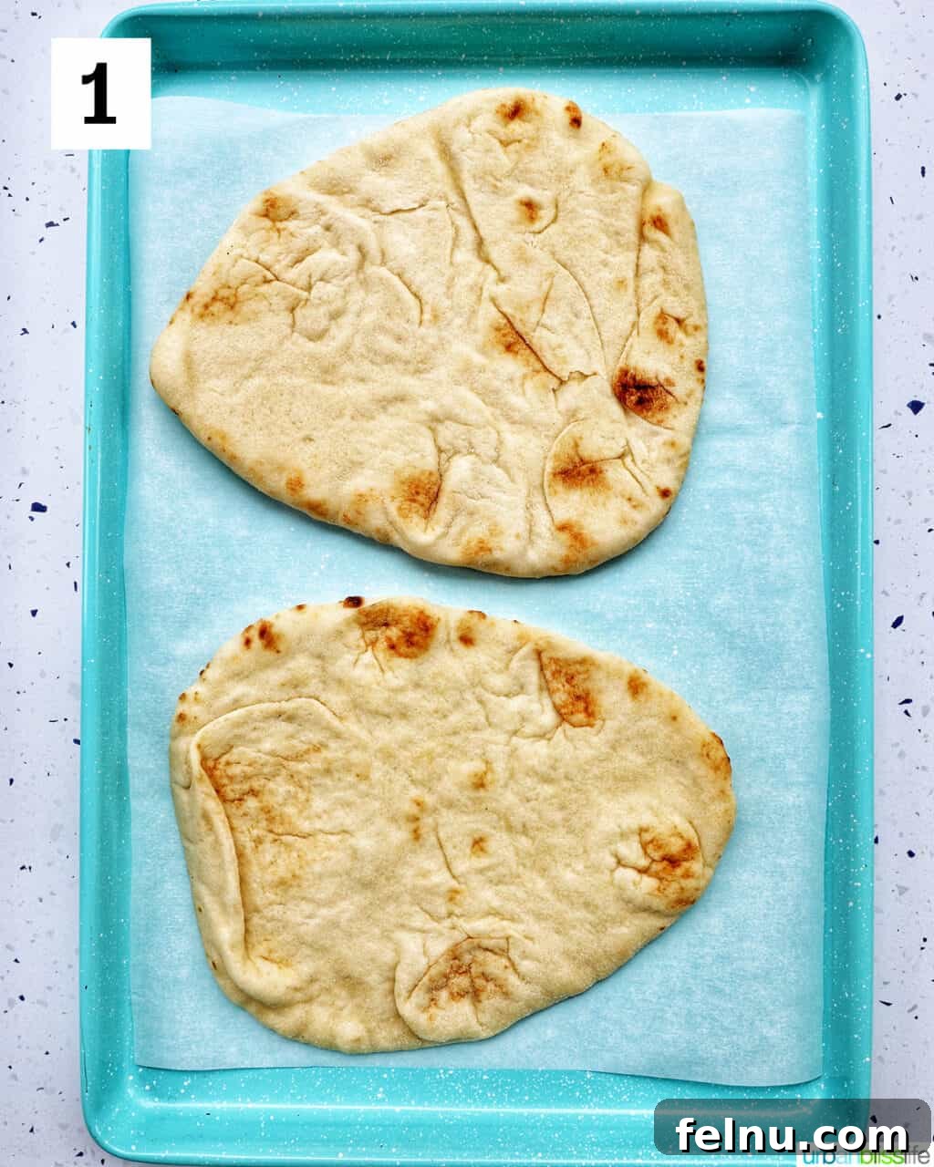 two naan flatbreads perfectly positioned on a baking sheet, ready for toppings.