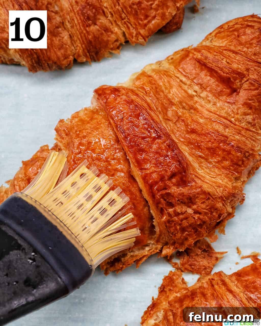 Brushing the baked croissant with the homemade syrup.
