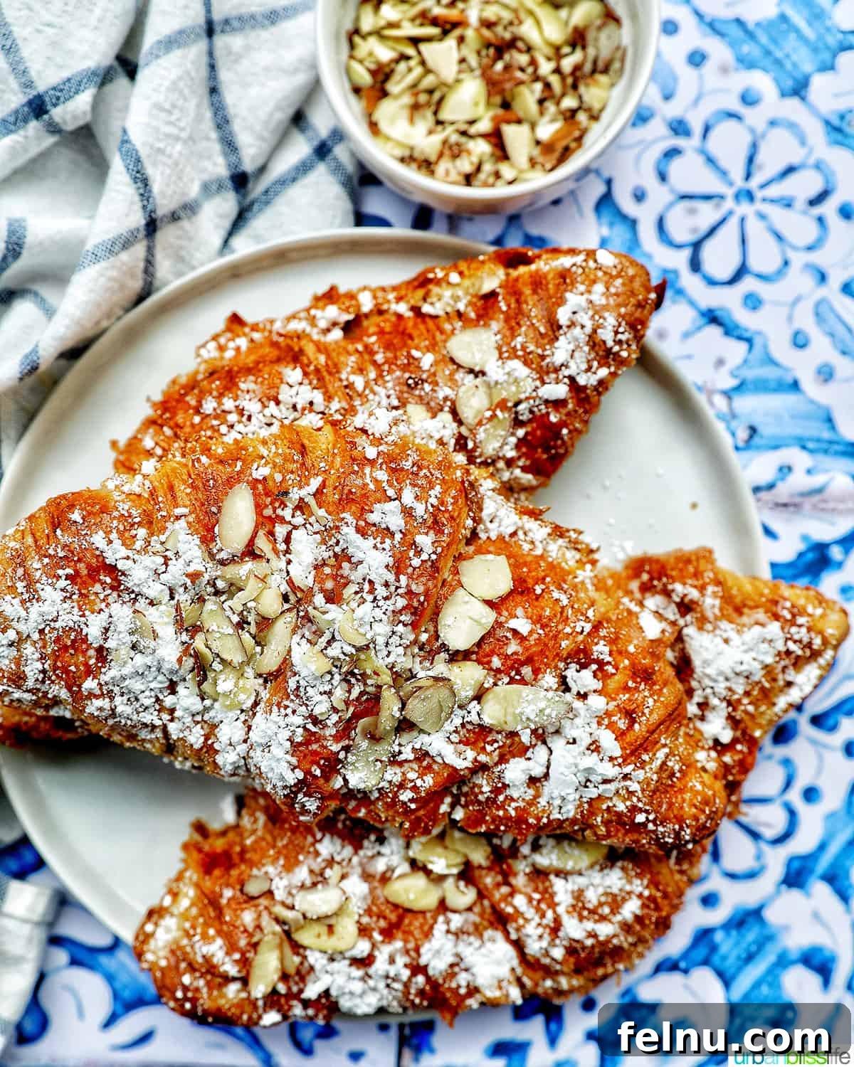 Three almond croissants elegantly arranged on a plate.