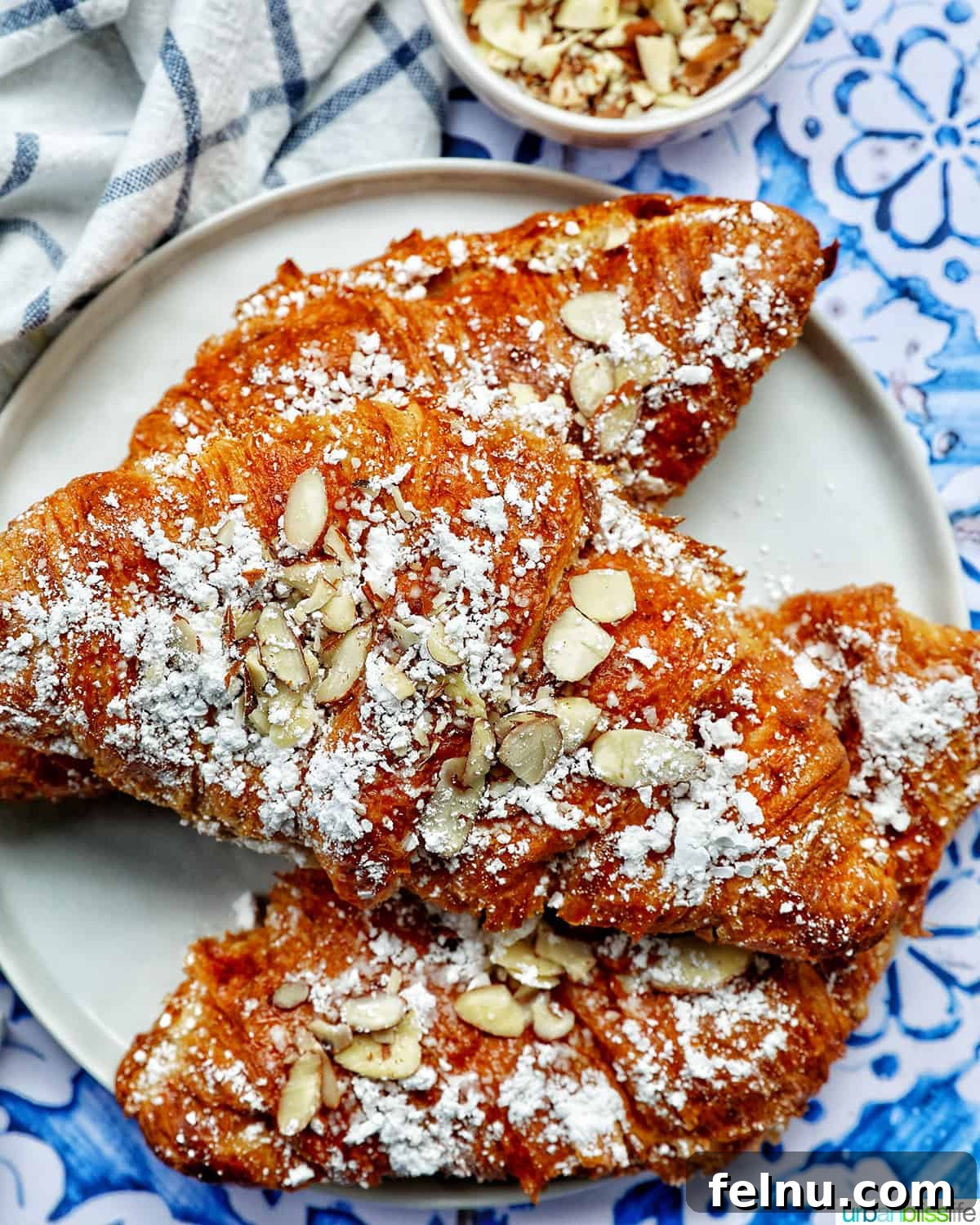 A close-up shot of three almond croissants, highlighting their flaky layers and almond topping.