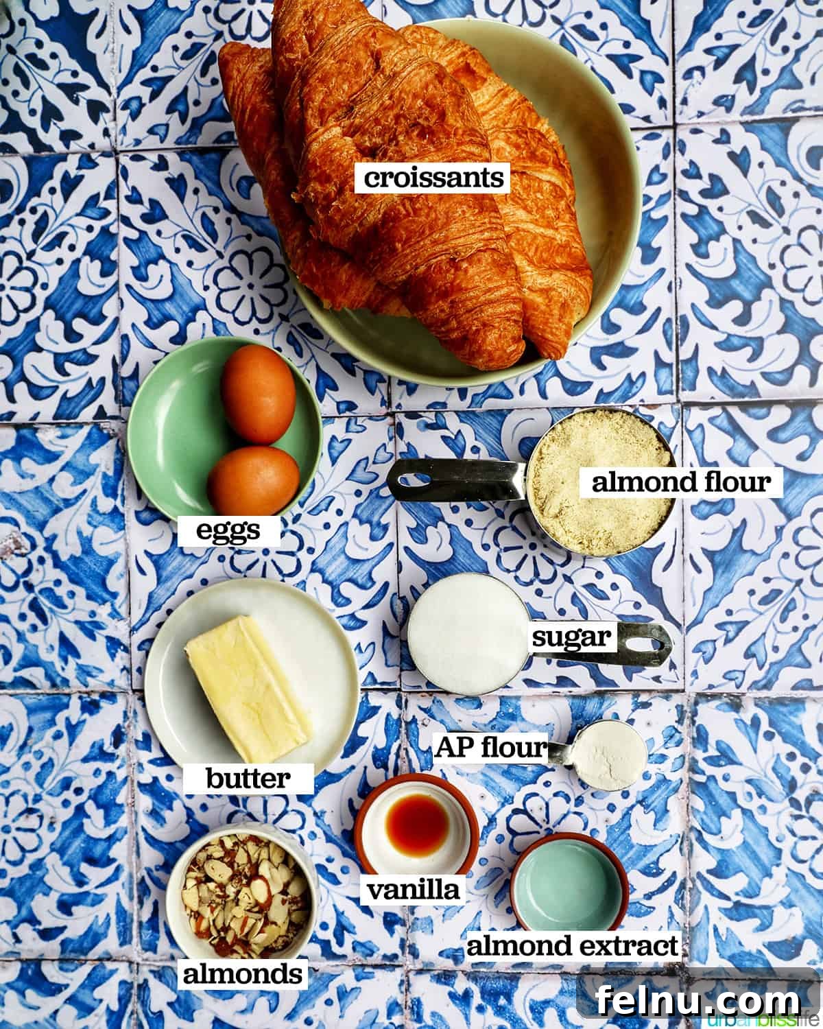 An array of ingredients required for making almond croissants, including croissants, almond flour, sugar, butter, and extracts.