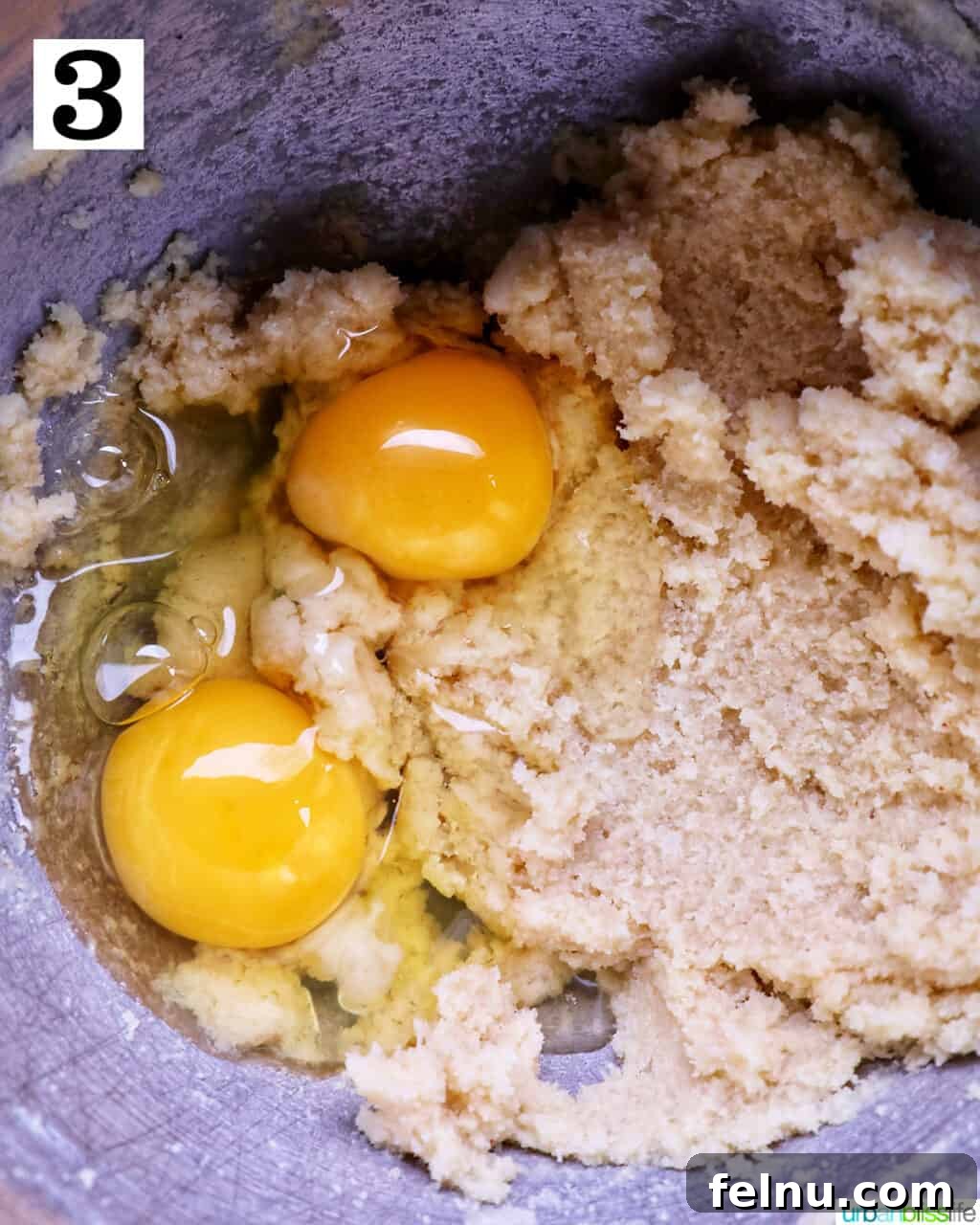 Adding egg yolks to the butter and sugar mixture.