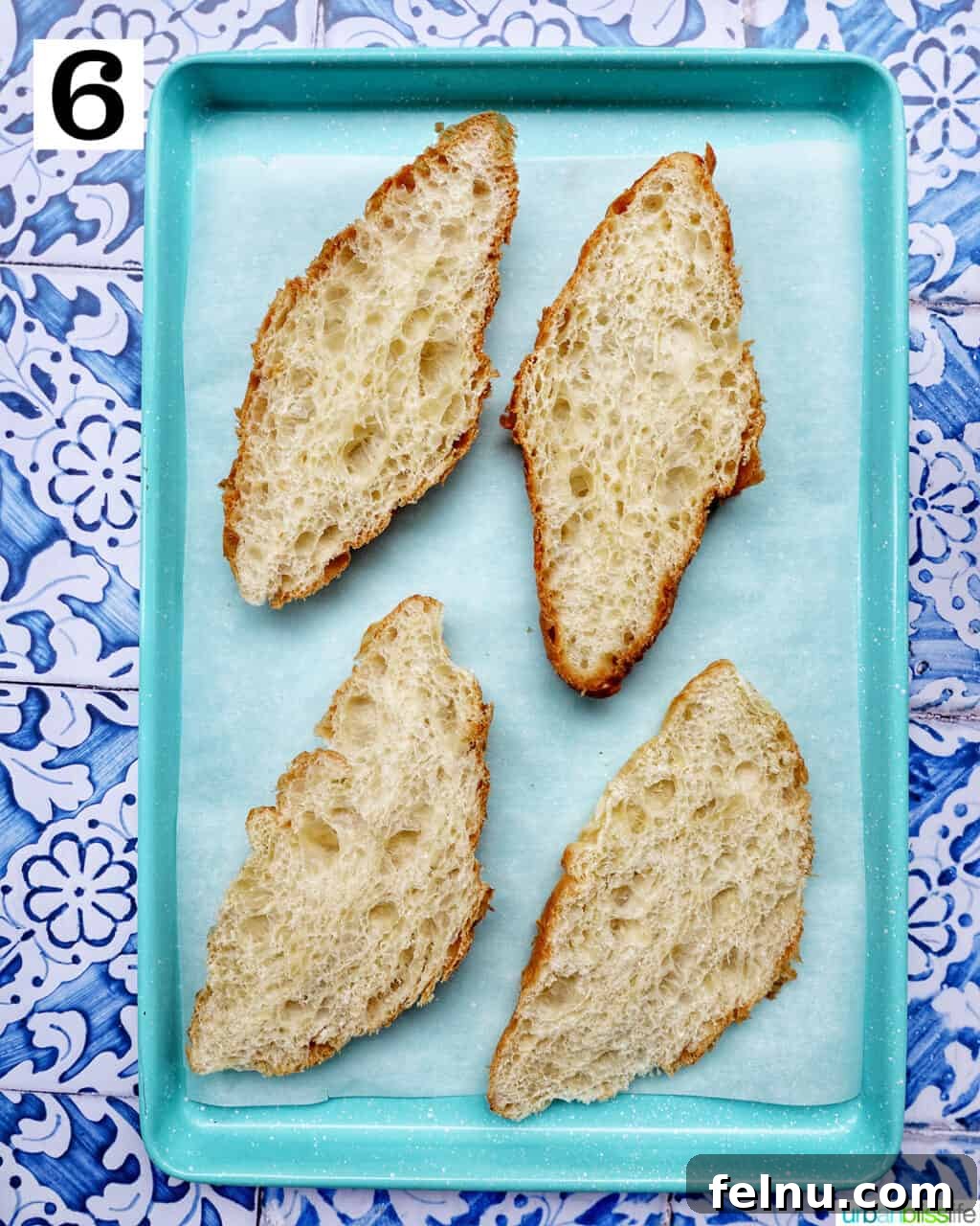 Croissants sliced in half and arranged on a baking sheet, ready for the filling.