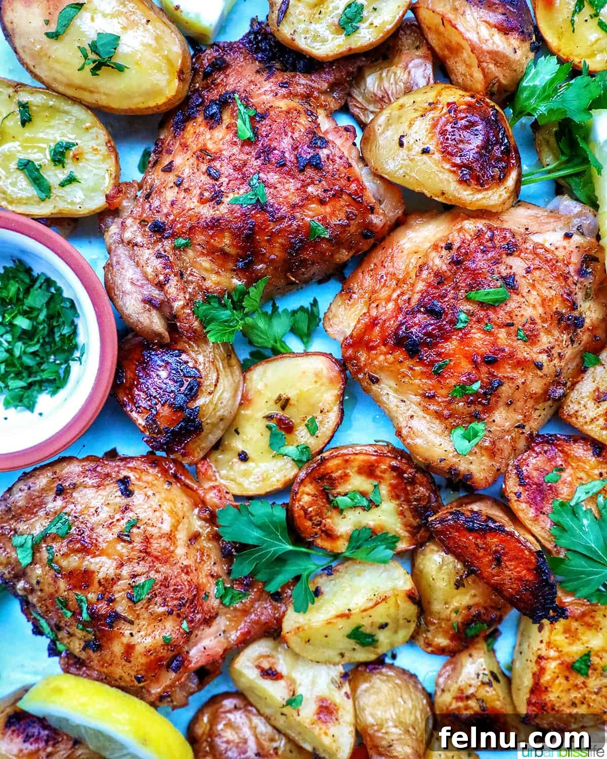 Tek Tepside Tavuklu Patates 2 chicken and potatoes garnished with parsley and lemon slices.