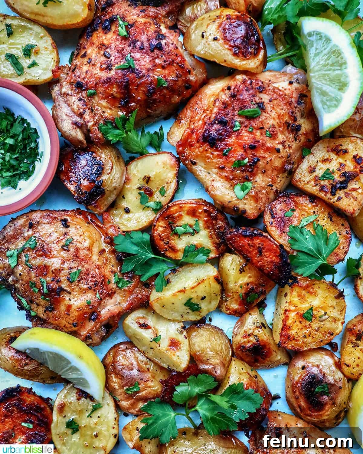 Tek Tepside Tavuklu Patates 12 chicken and potatoes garnished with parsley and lemon slices.