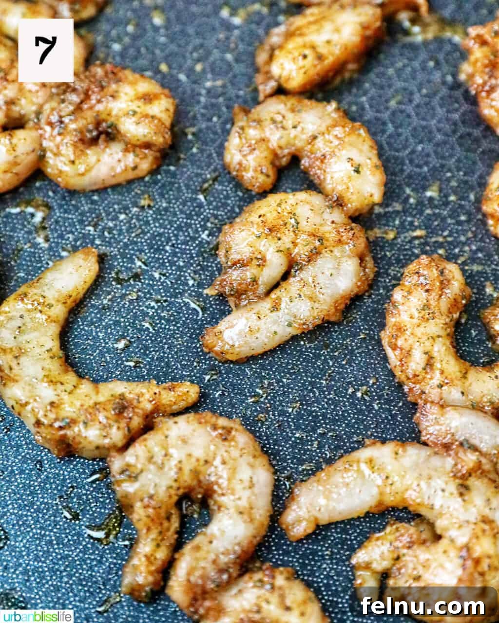 Seasoned shrimp cooking in a pan.