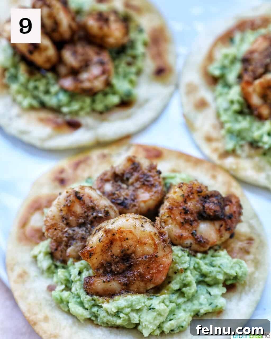 Tortillas topped with guacamole and shrimp.