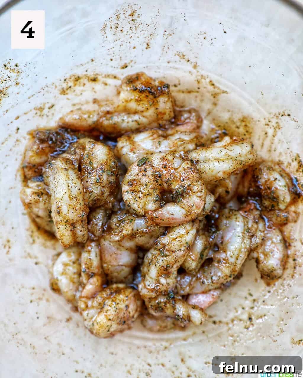 Seasoning raw shrimp in a bowl.