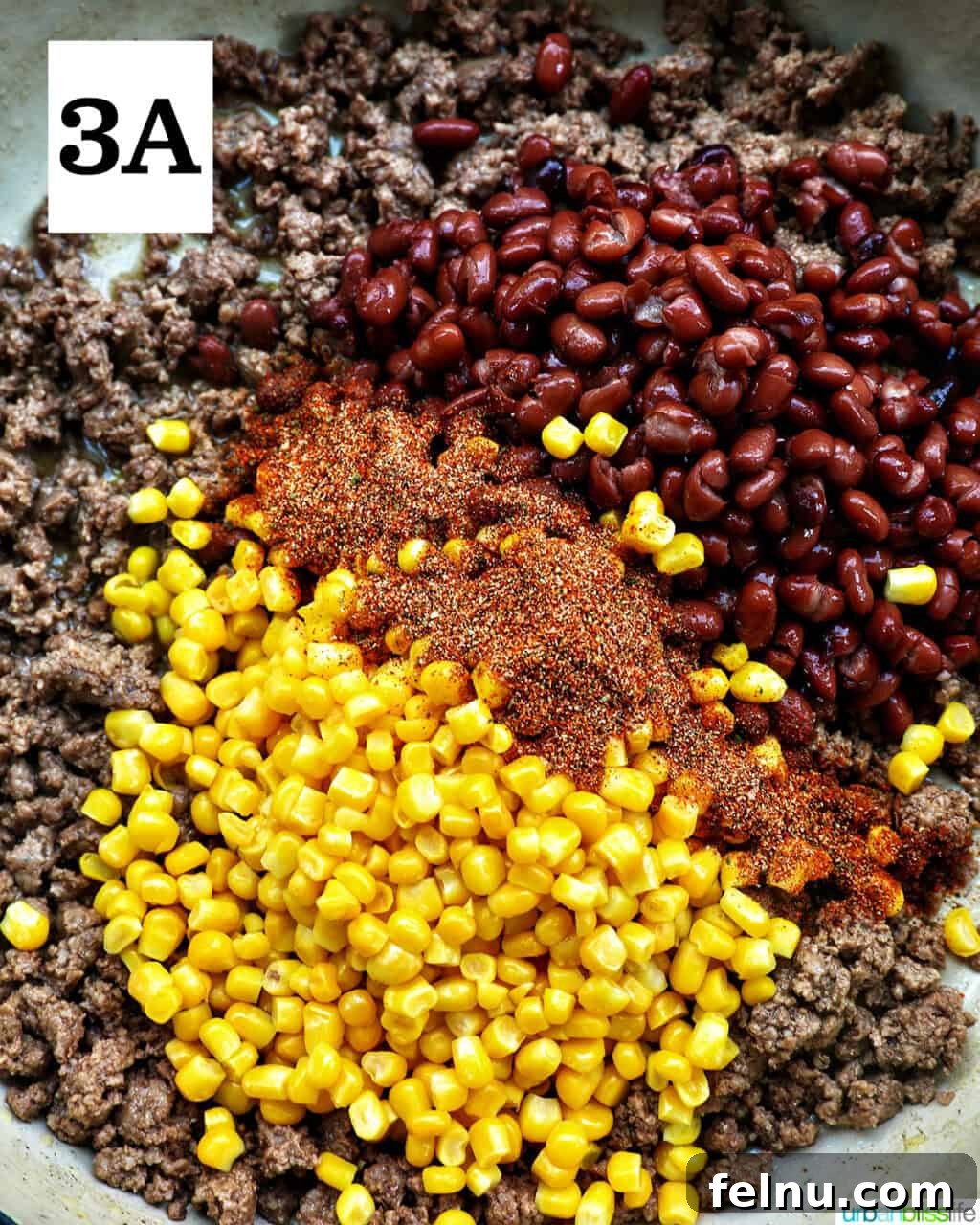 Effortless Fiesta Bowls 7 Corn, seasonings, and beans added to cooked ground beef in a pan.
