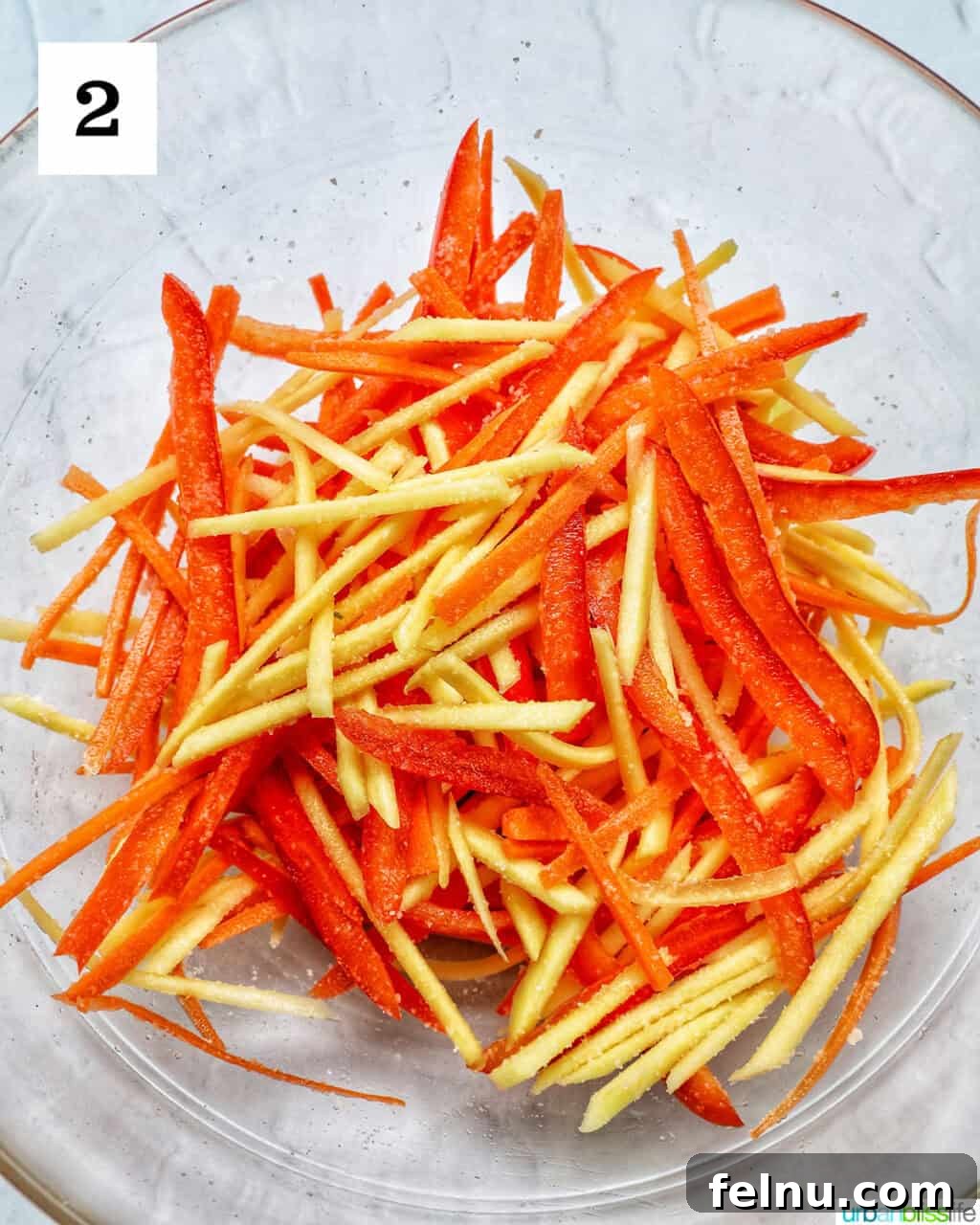 Filipino Atchara: Sweet and Sour Papaya Pickle 6 Close-up of julienned papaya, carrots, and red bell pepper in a large mixing bowl.