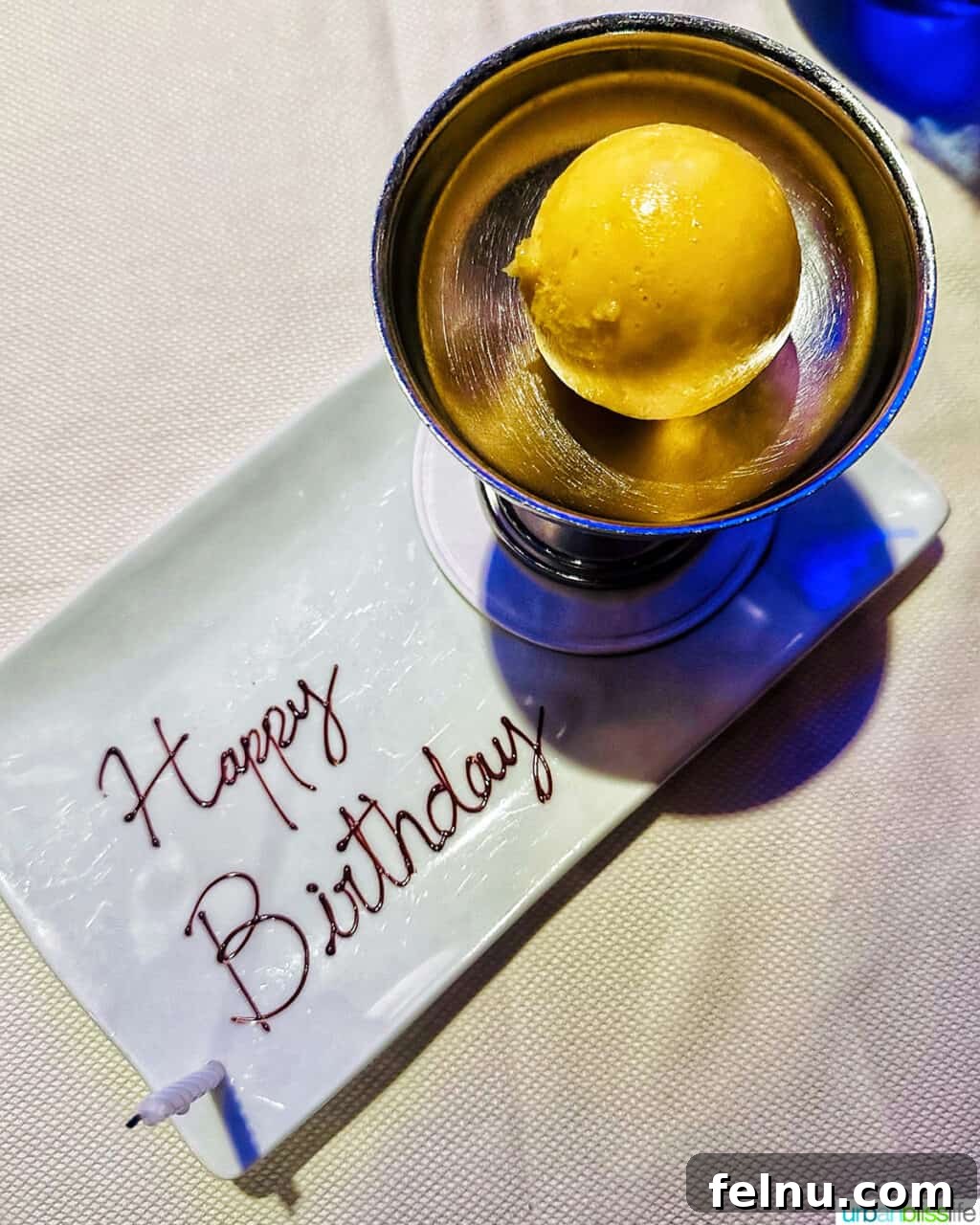 Yuzu sorbet in a bowl with a plate that has Happy Birthday written in chocolate at Marea restaurant New York City (NYC).