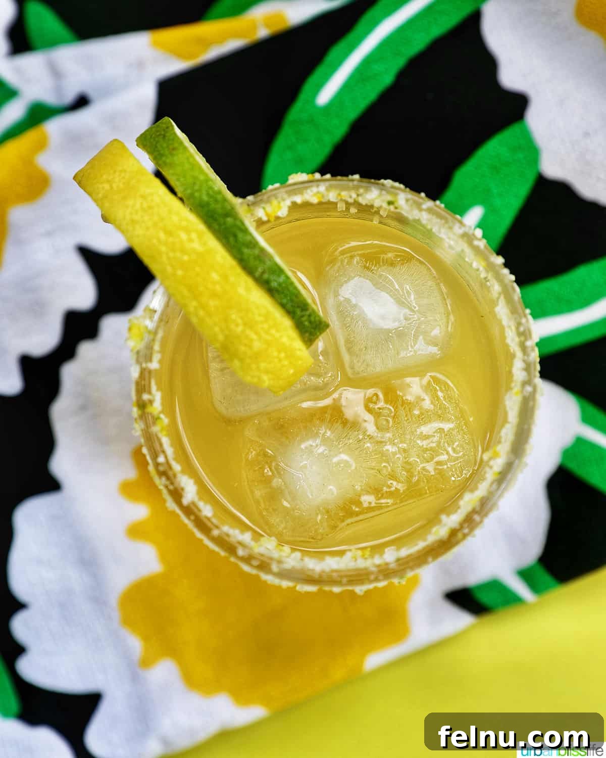 Zesty Yuzu Margarita 2 A vibrant Yuzu Margarita garnished with fresh lemon and lime slices, set on brightly colored napkins, inviting a taste of summer.