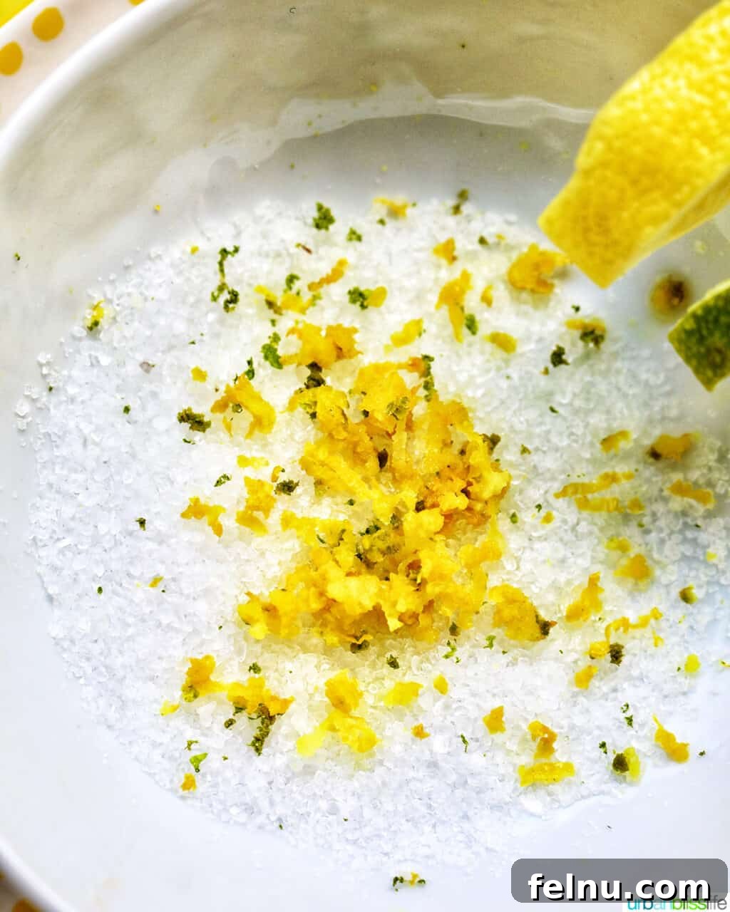 Zesty Yuzu Margarita 6 A close-up shot of a bowl filled with vibrant lime zest, lemon zest, and coarse sea salt, ready to rim a margarita glass.
