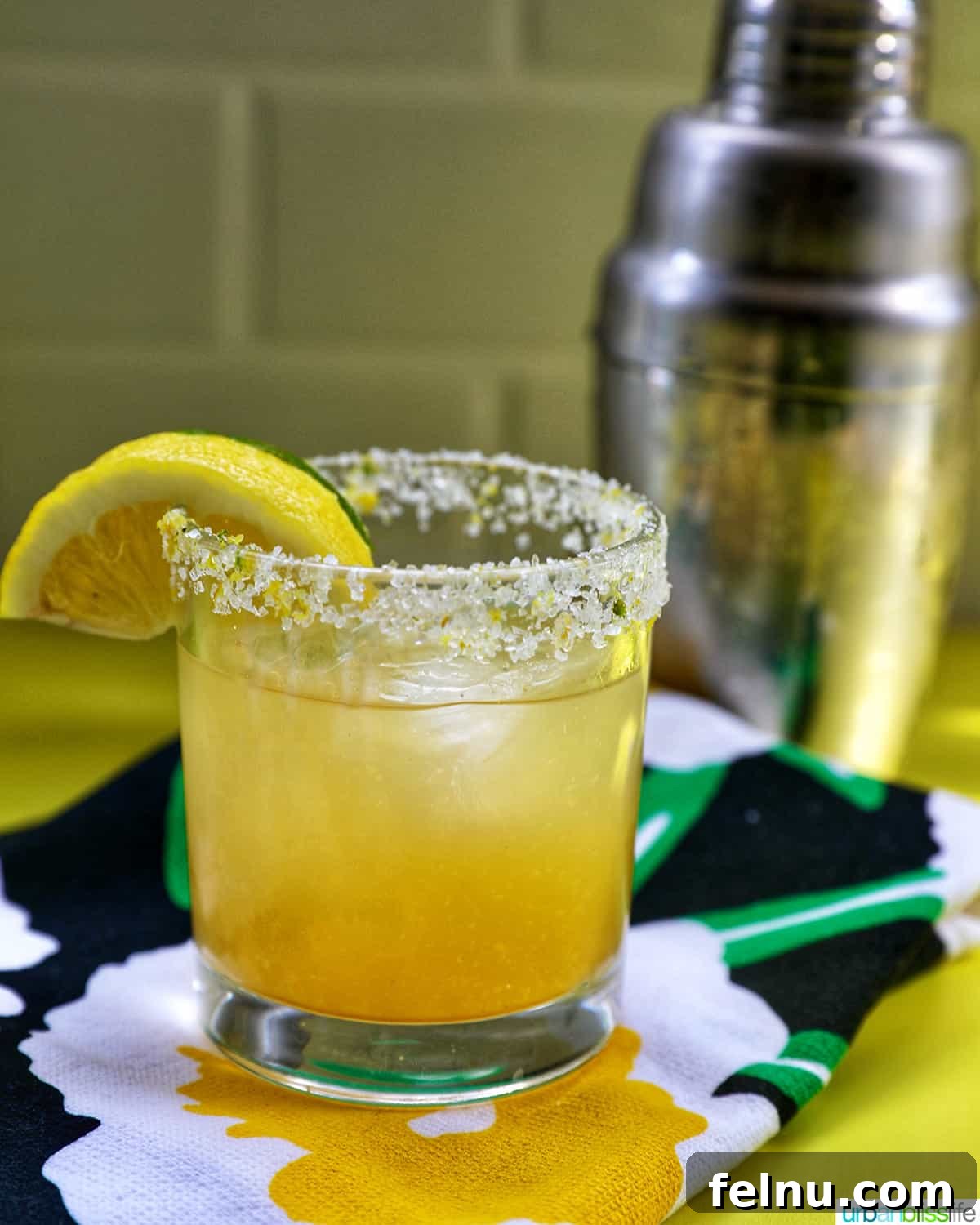 Zesty Yuzu Margarita 10 A perfectly prepared Yuzu Margarita in a cocktail glass, next to a sleek stainless steel shaker, ready for the next delicious pour.