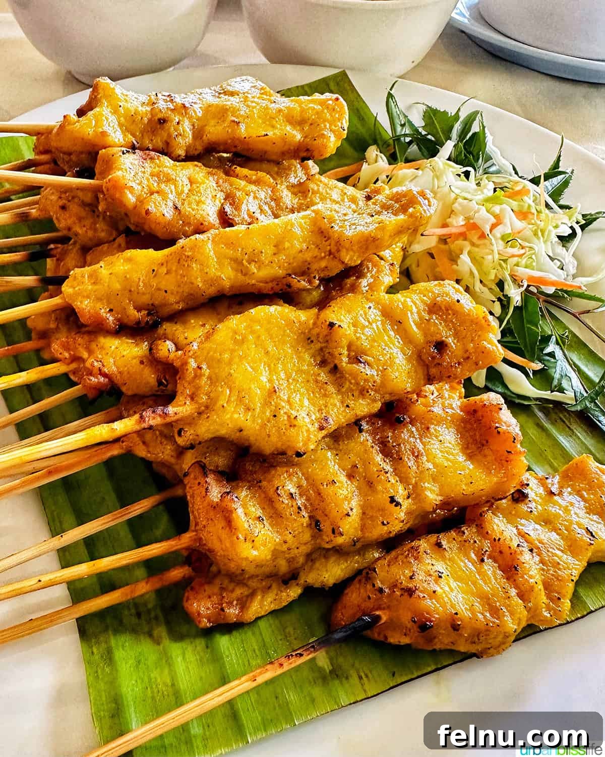 Must-Try Thai Dishes 11 stacks of chicken satay skewers on banana leaves.