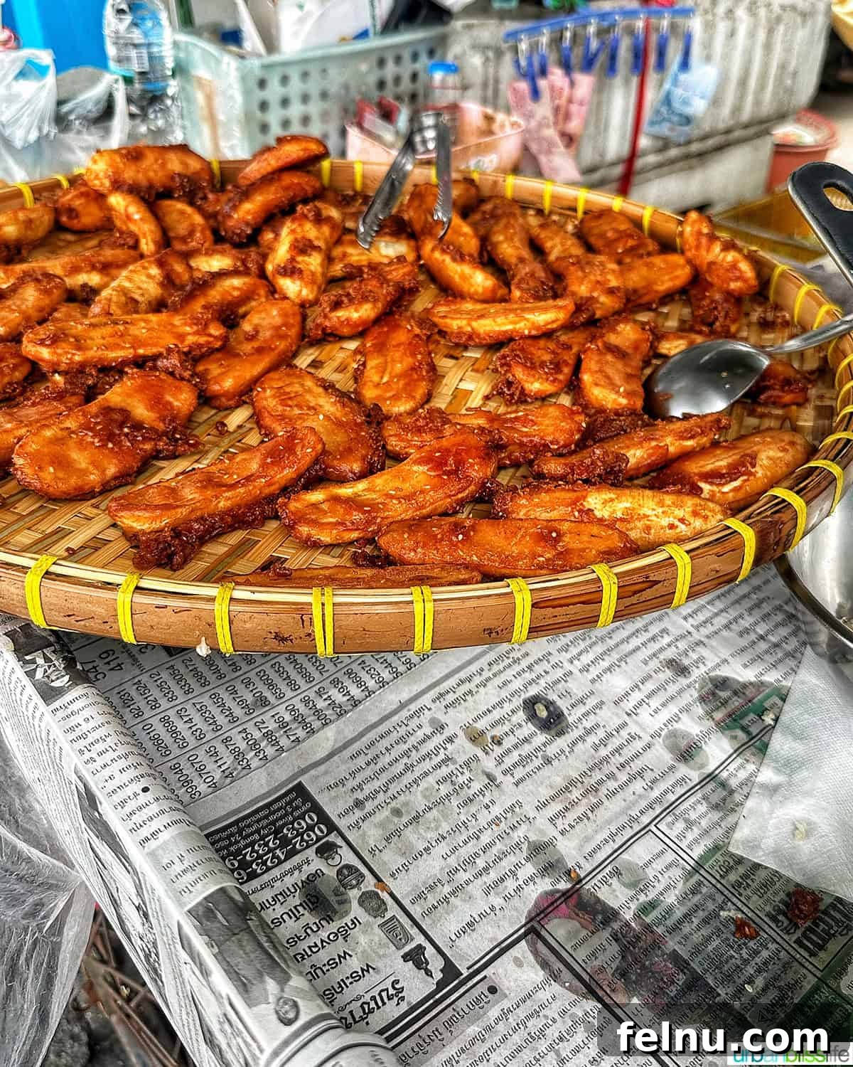 Must-Try Thai Dishes 24 Thai fried bananas in a large platter on top of oil-stained newspapers after being fried.