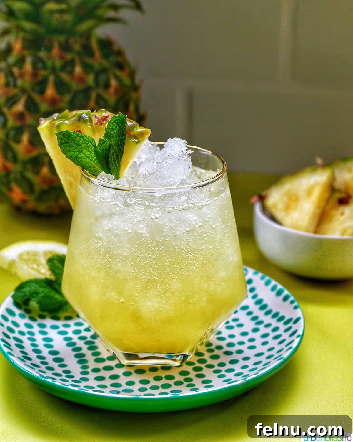 A close-up of a Pineapple Mocktail with mint leaves and a pineapple slice.
