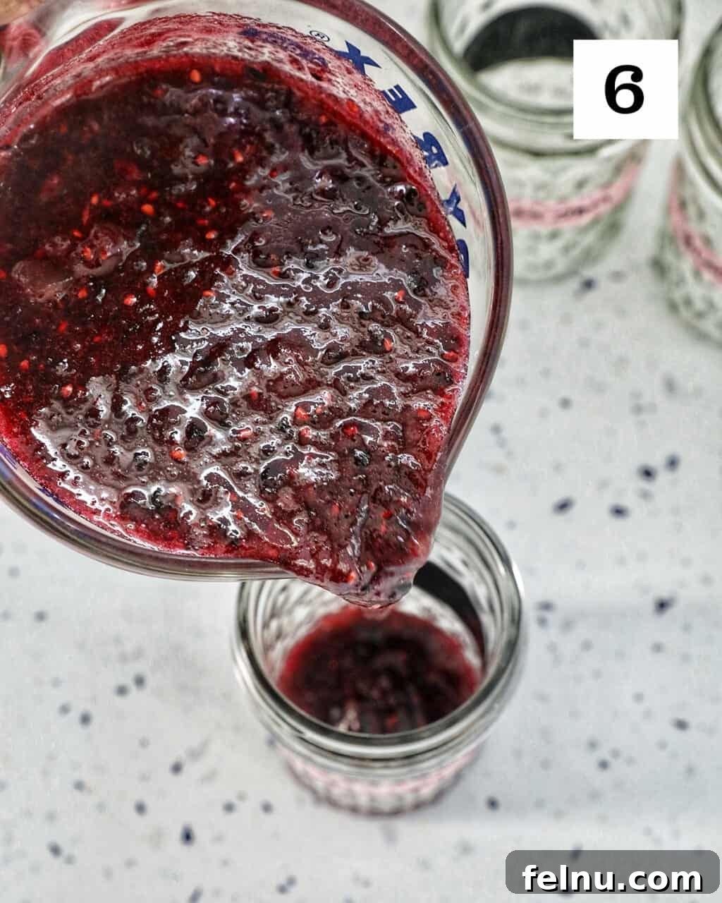 Homemade No-Cook Blackberry Jam 15 pouring blackberry freezer jam into a mason jar.