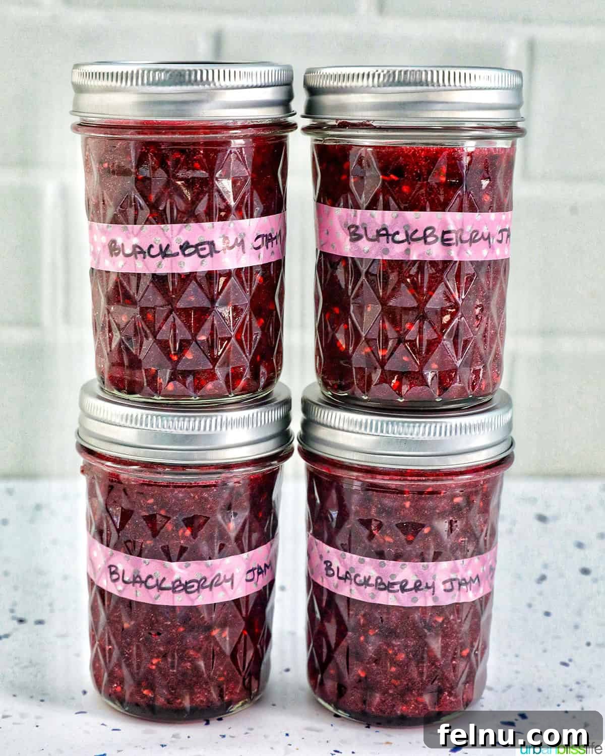 Homemade No-Cook Blackberry Jam 4 four mason jars of blackberry freezer jam, stacked.