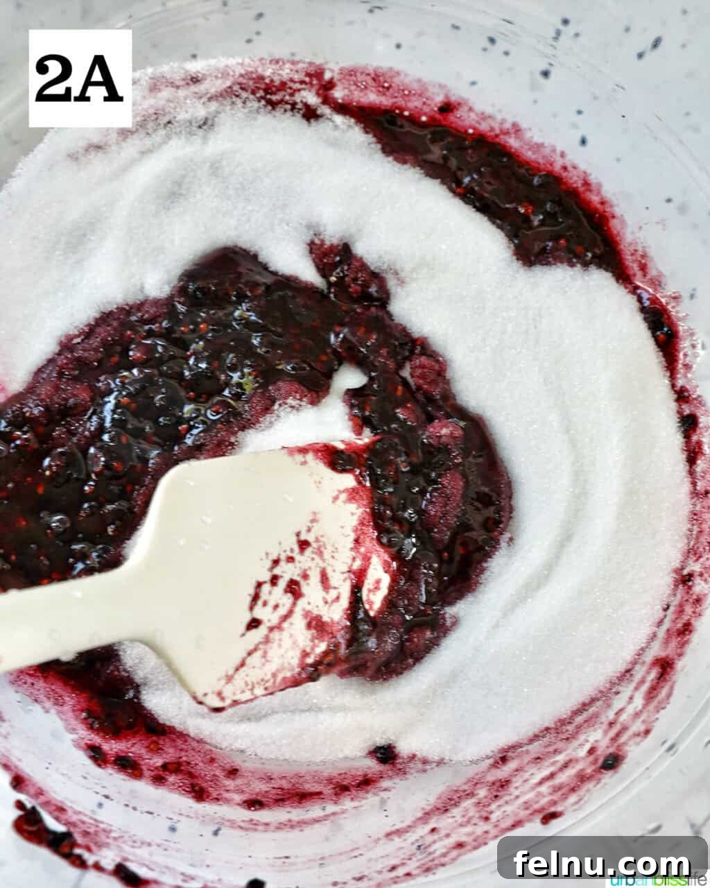 Homemade No-Cook Blackberry Jam 8 spatula swirling blackberry jam and sugar.