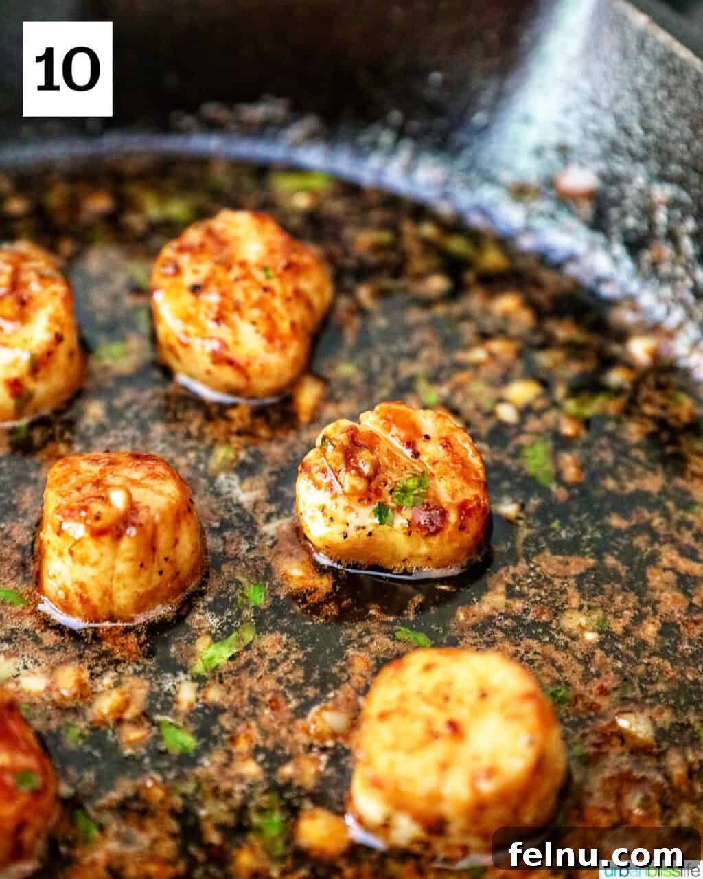 Seared scallops in a cast iron skillet with butter garlic herb sauce.