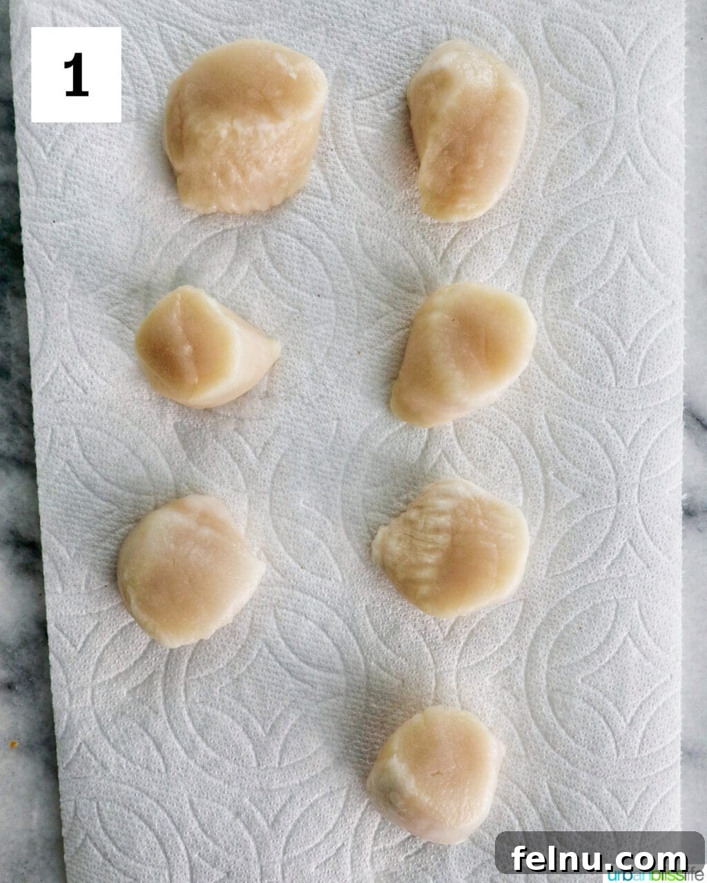 Raw scallops on a paper towel.