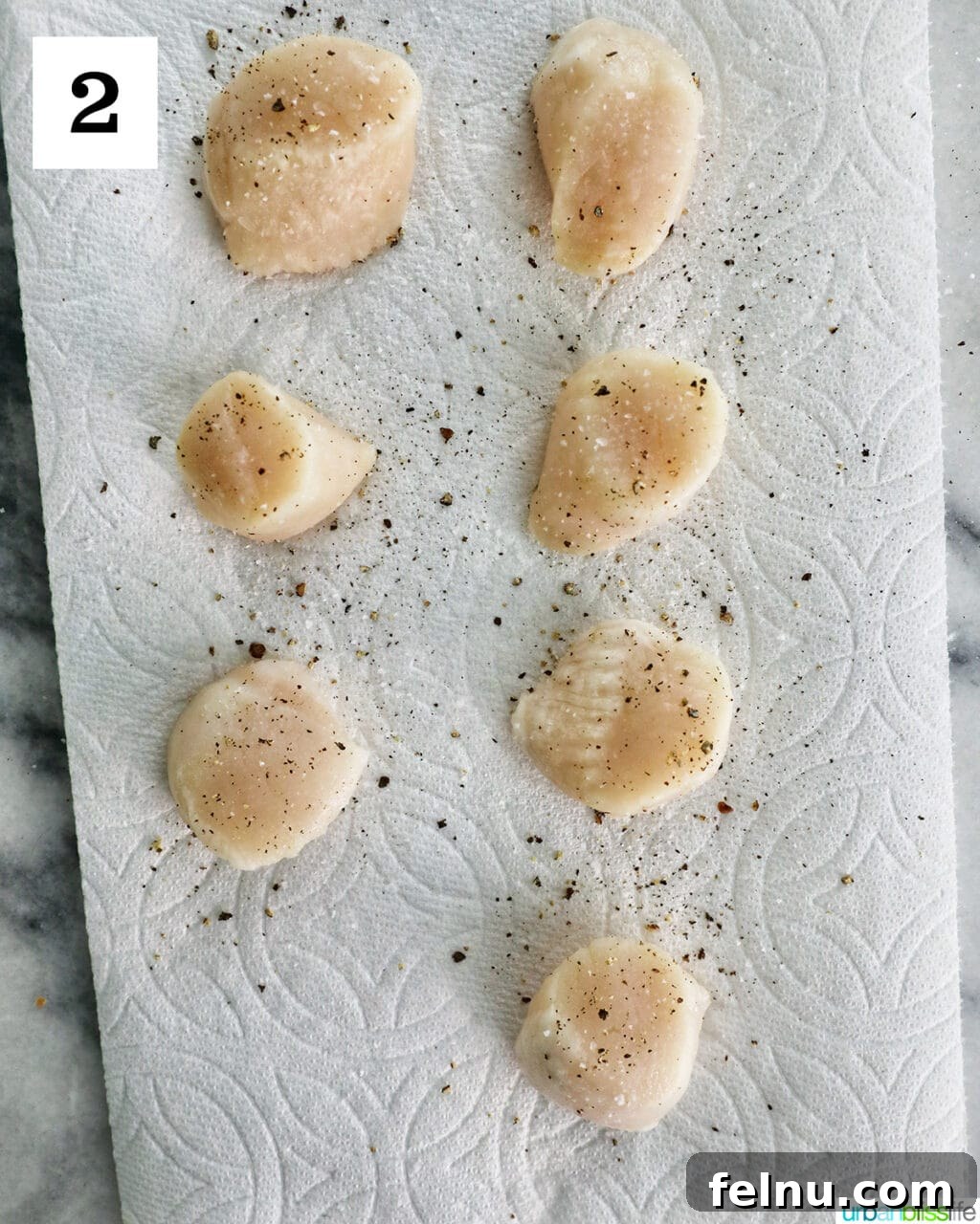Seasoned raw scallops on a paper towel.