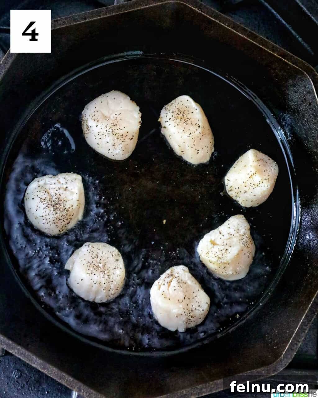 Several scallops in a cast iron skillet.