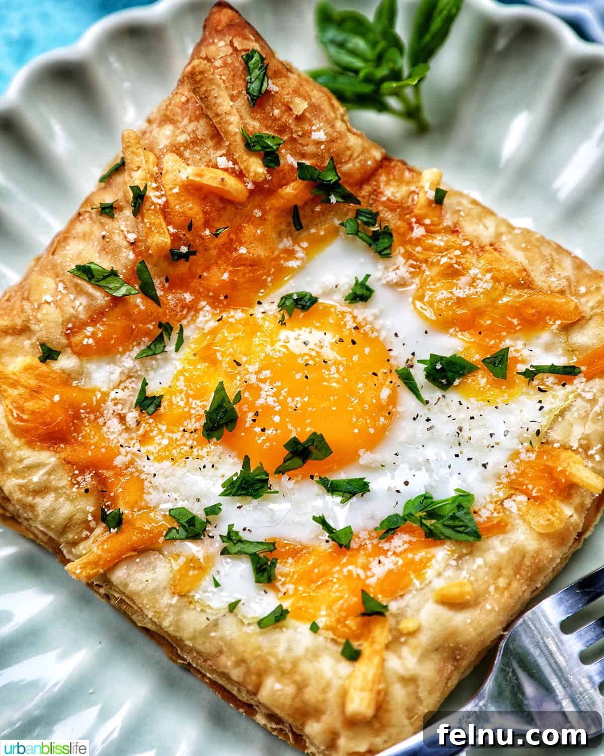 Golden Egg Parcels 2 Close-up of a golden-brown egg in puff pastry, garnished with fresh parsley.