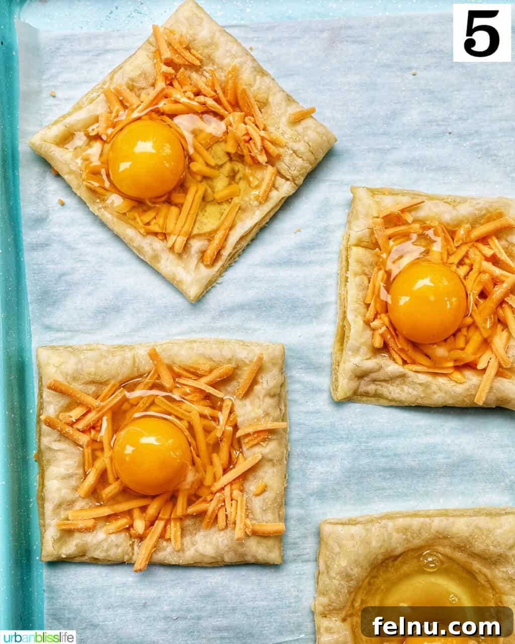 Golden Egg Parcels 11 A baking sheet with four puff pastry squares, each filled with cheese and an egg, ready for the second bake.
