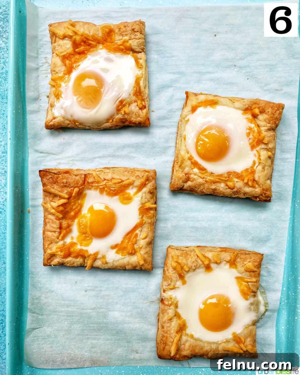 Golden Egg Parcels 12 Baked eggs in puff pastry squares, golden brown and cooked, on a baking sheet.
