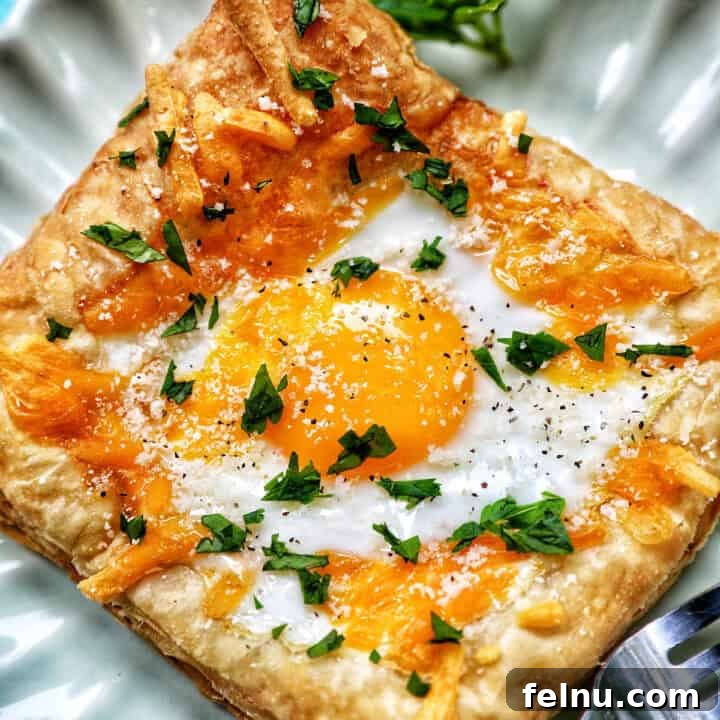 Golden Egg Parcels 19 Egg in puff pastry on a plate with parsley garnish.
