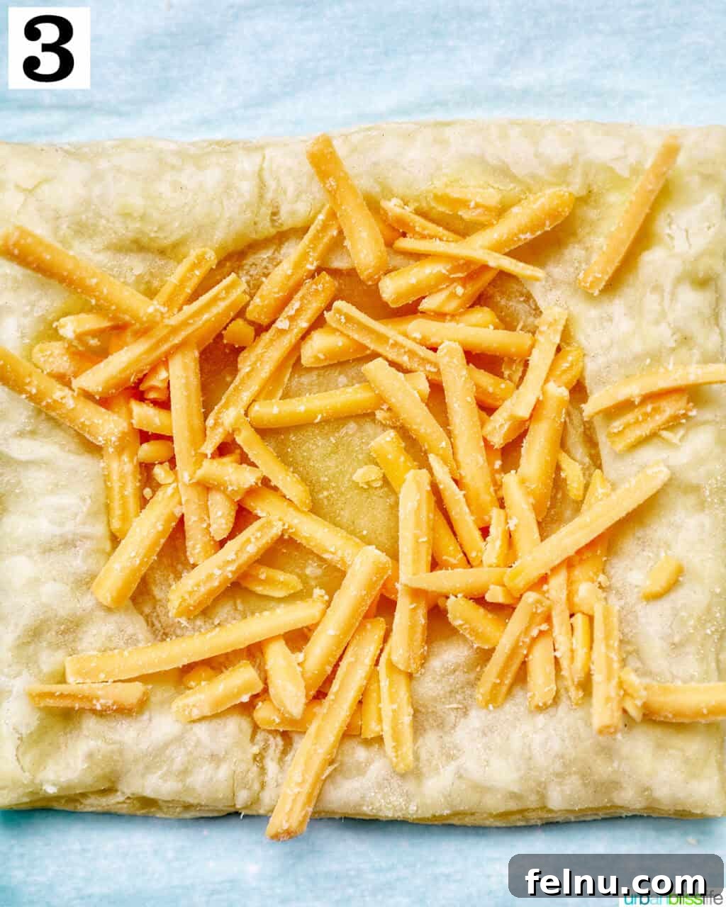 Golden Egg Parcels 9 Shredded cheddar cheese sprinkled over the indentation of a puff pastry square.