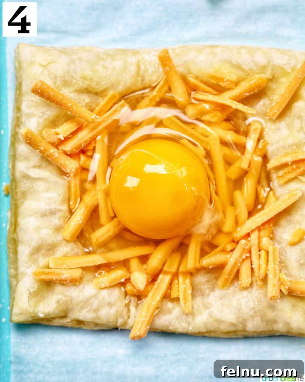 Golden Egg Parcels 10 A raw egg carefully placed on top of shredded cheddar cheese within a puff pastry square.
