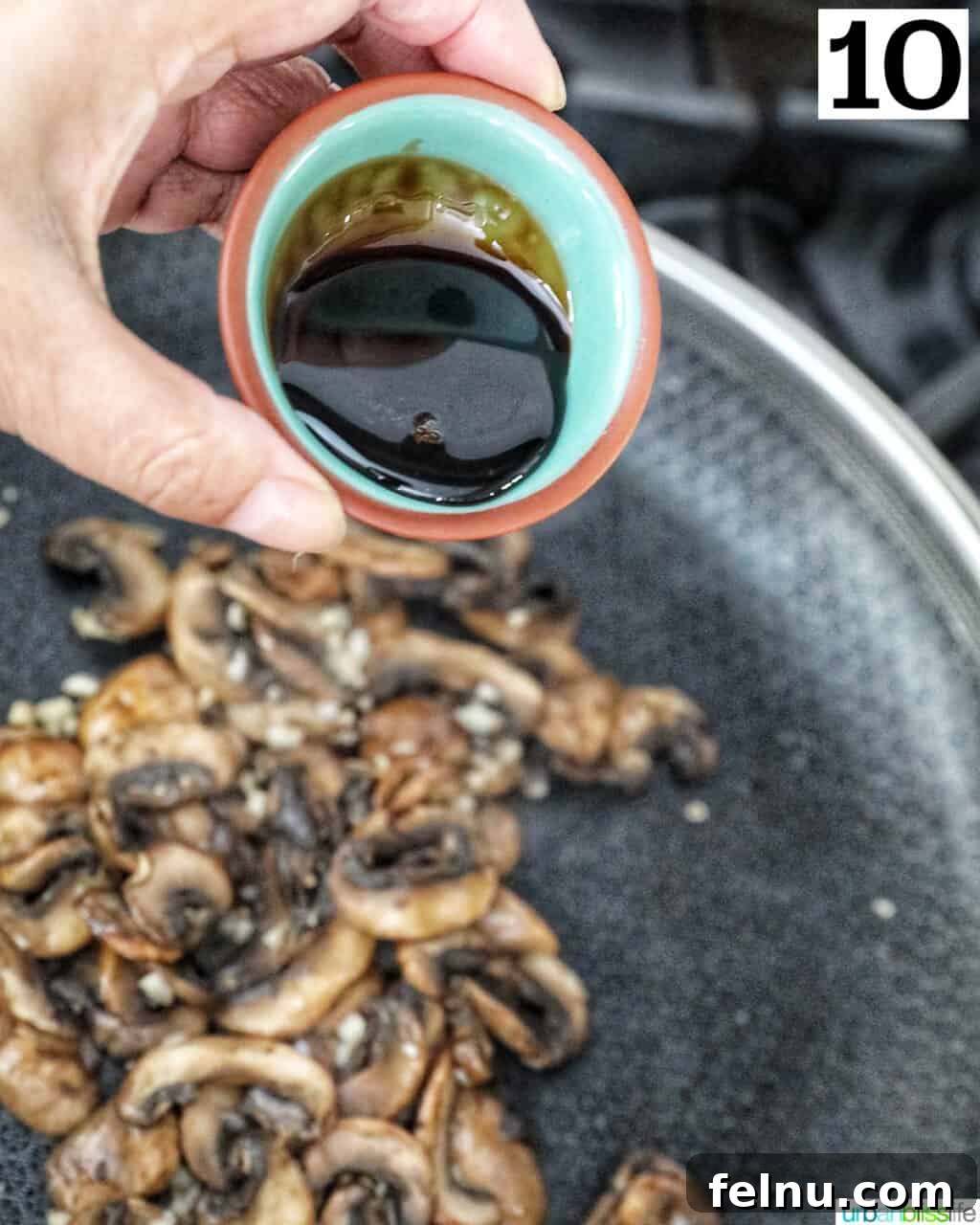 Savory Mushroom Toasts 14 A hand pouring a small bowl of balsamic glaze over sliced mushrooms in a cast iron skillet.