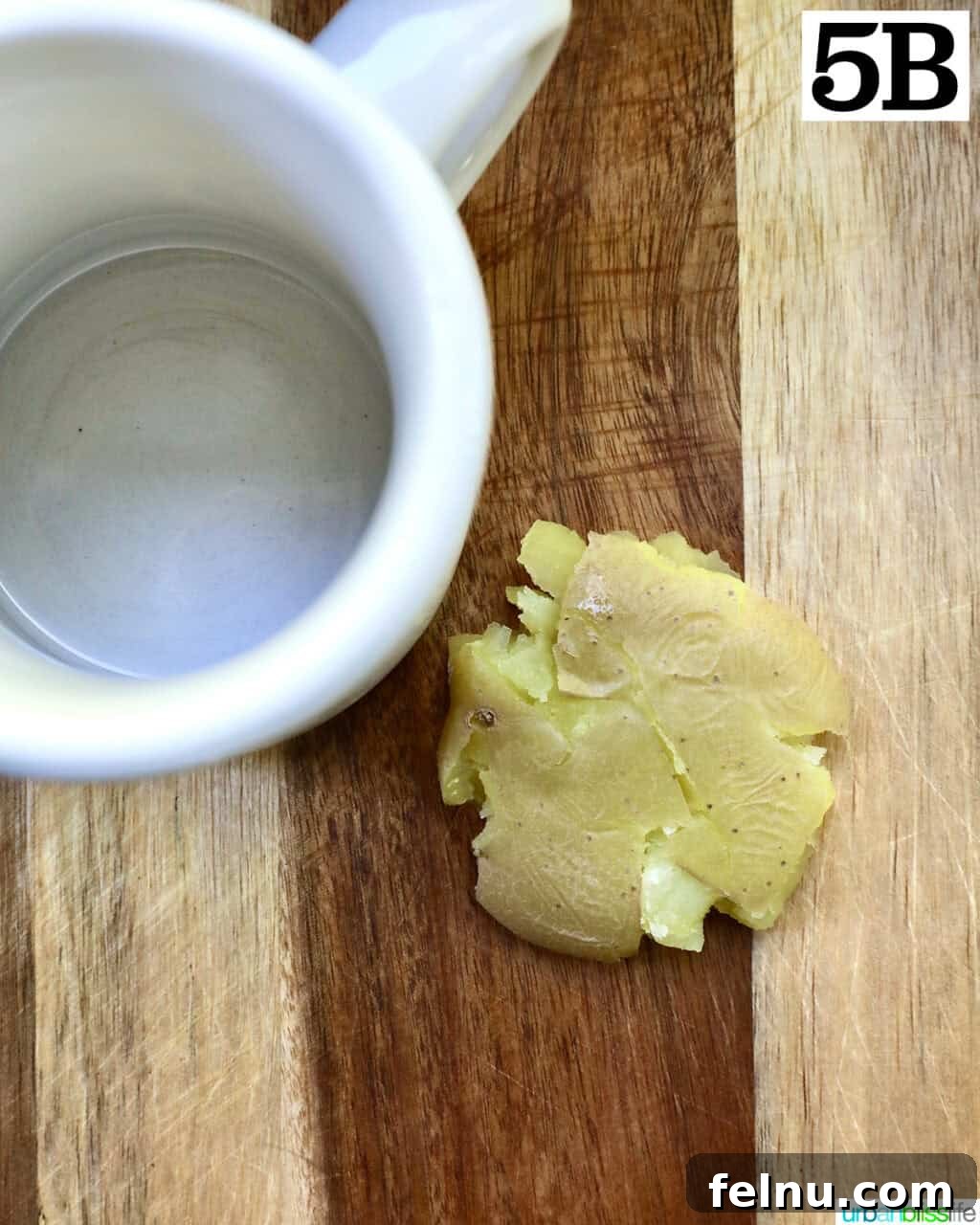 Crispy Air-Fried Smashed Potatoes 11 A single smashed baby potato, flattened with a white mug, resting on a cutting board.