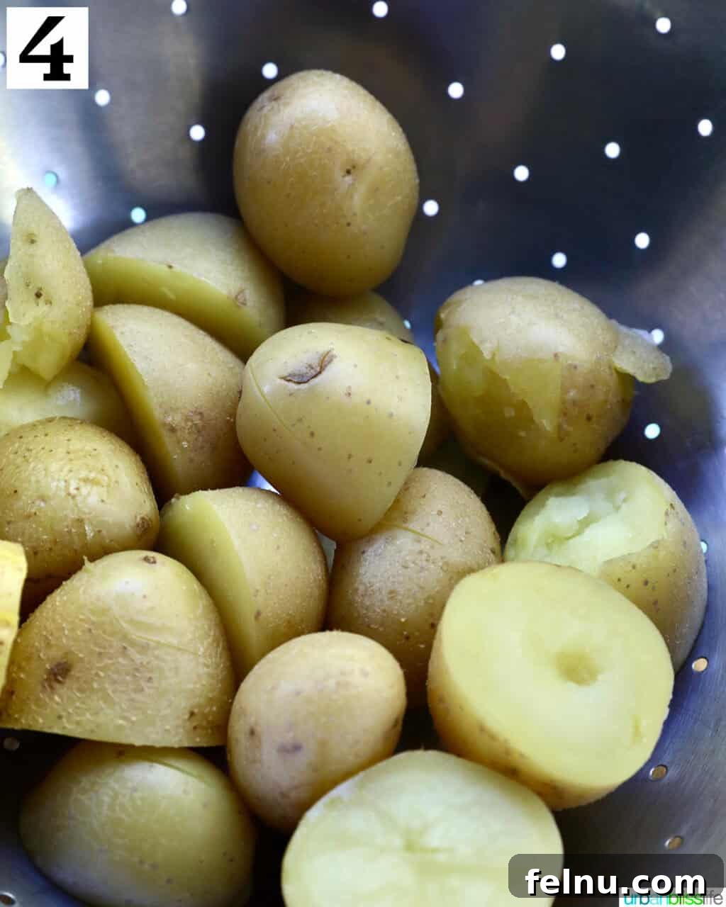 Crispy Air-Fried Smashed Potatoes 9 Freshly boiled baby potatoes being drained in a metal strainer, steam rising.
